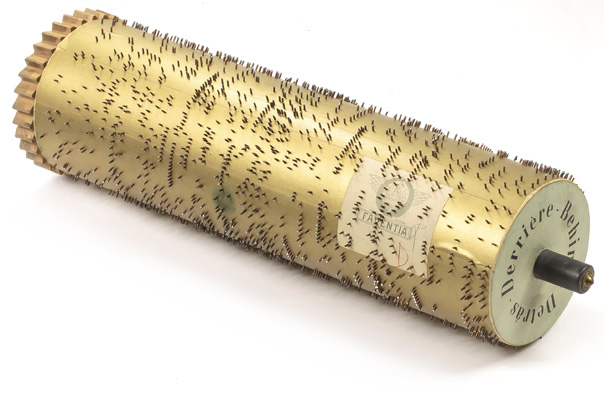 Large wooden cylinder covered in gold-colored foil with metal pins for the Faventia Street Piano