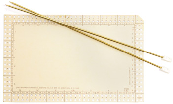 Large blank card with holes around the outside edge and two needles to be used for sorting